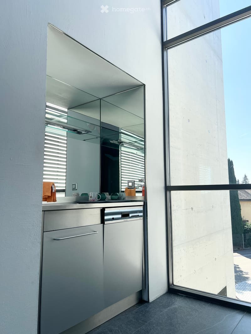Modern kitchen with stainless steel dishwasher, white cabinets, and a countertop with cups and a towel.