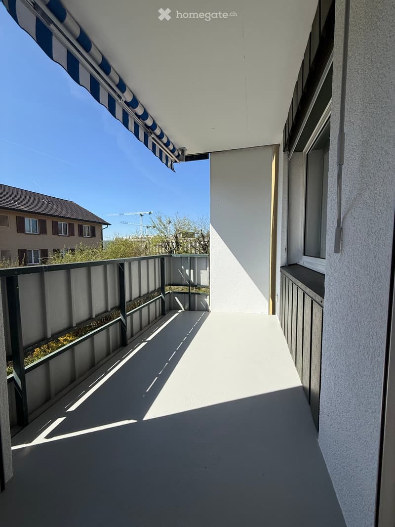 empty balcony with metal railings, white floor, blue and white striped awning