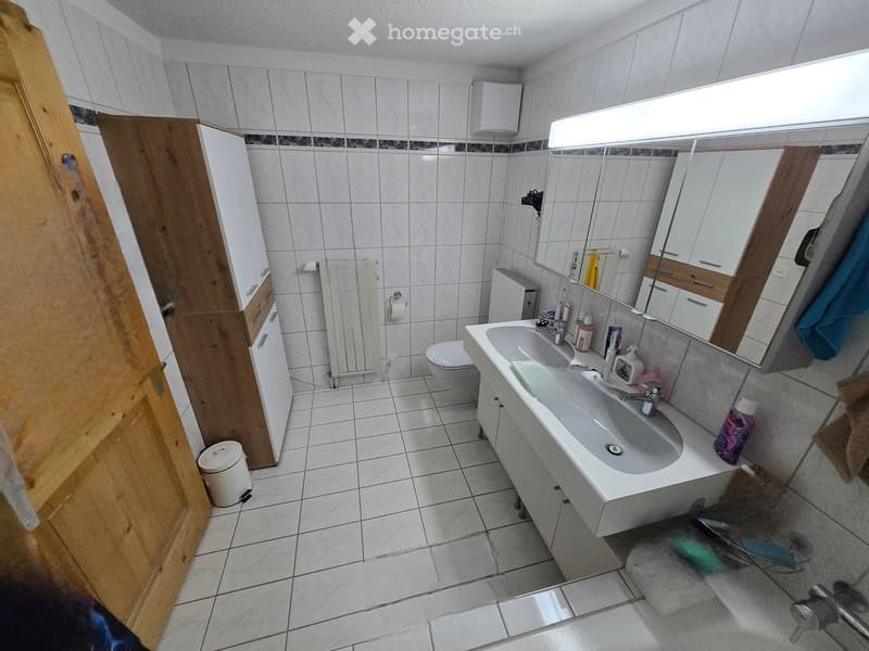 Bathroom. Modern bathroom with white tiles, double sink, mirror, cabinet, toilet, and radiator.
