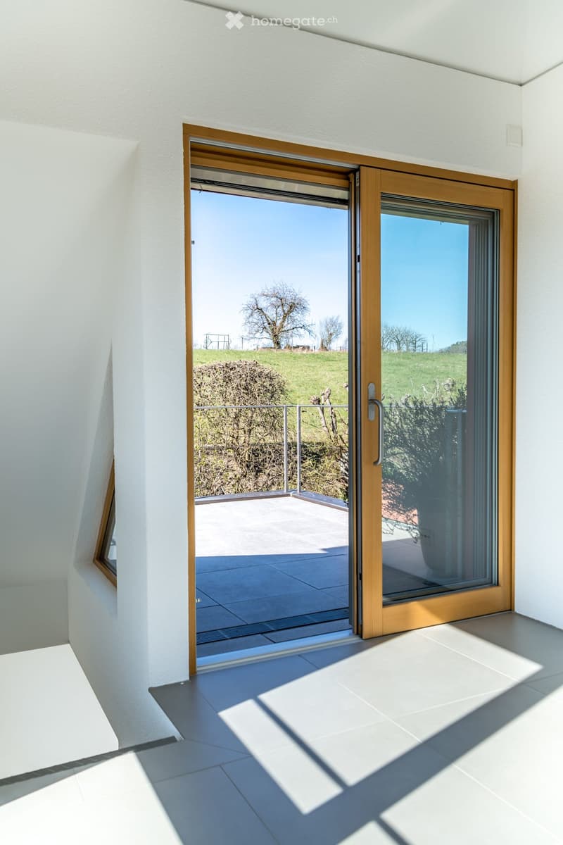 open sliding glass door leading to balcony, with large windows