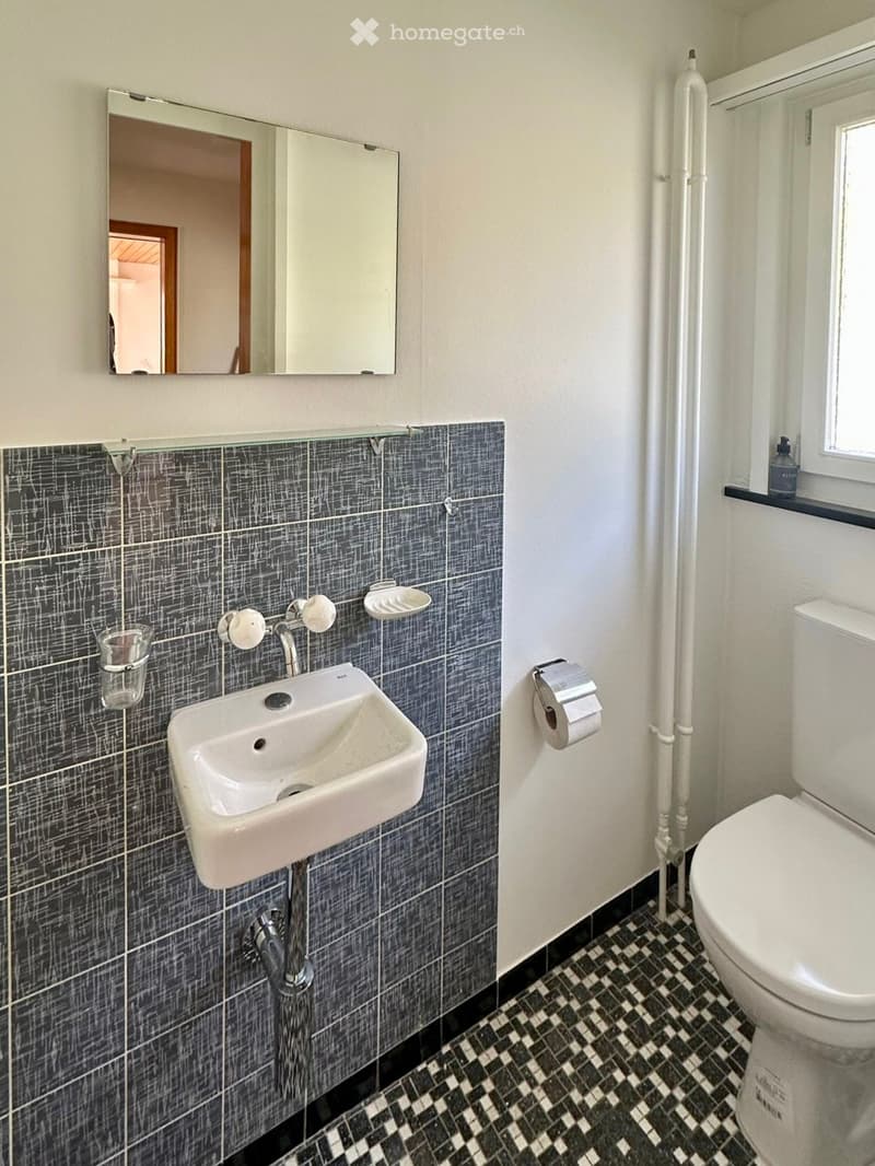 Bathroom with white sink, mirror, toilet, and tiled floor