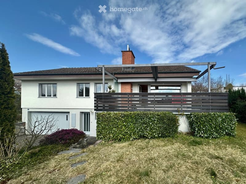 2 story house, white exterior, brown roof, brick chimney, garage, wooden fence, hedges, lawn