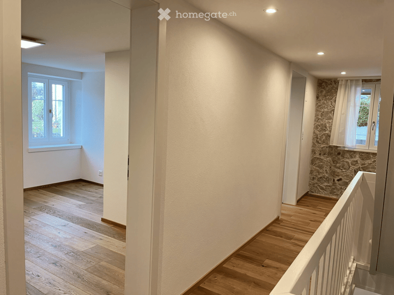 hardwood flooring, white walls, ceiling light fixtures, windows, open space, hallway
