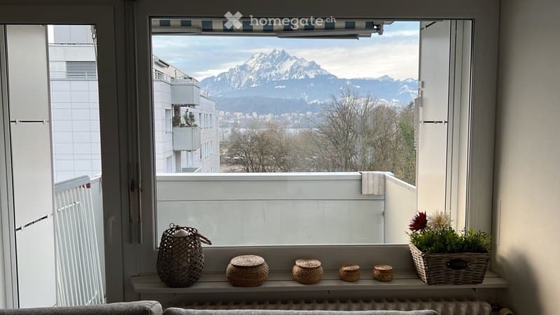 Balcony with a scenic mountain view, decorated with a basket and flower pot on the windowsill.