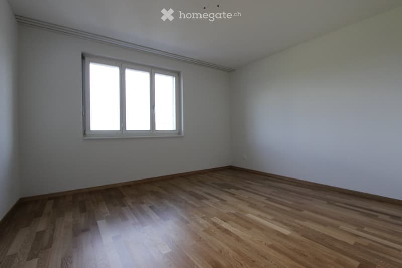 Empty room with wooden flooring and a large window, no furniture or equipment present.