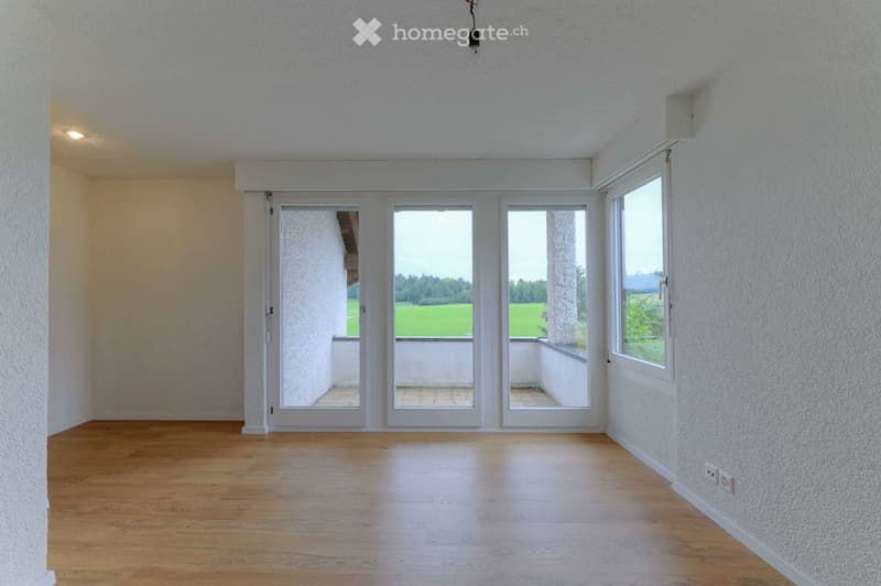 empty room, wooden floor, white walls, sliding glass doors leading to balcony, power outlets, natural light