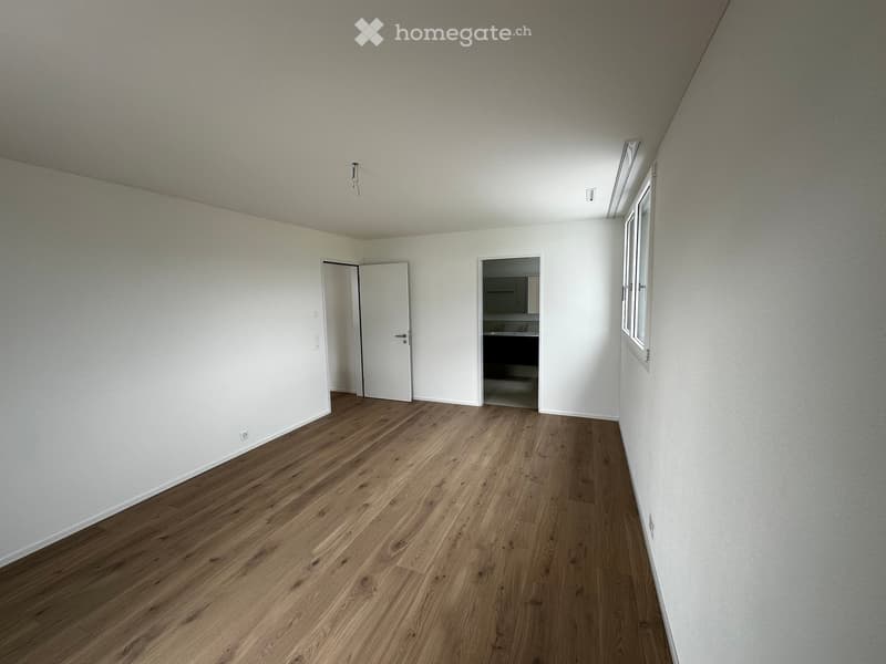 Empty room with wooden flooring, white walls, and two doors leading to other spaces. The room is completely unfurnished with no visible furniture or equipment.