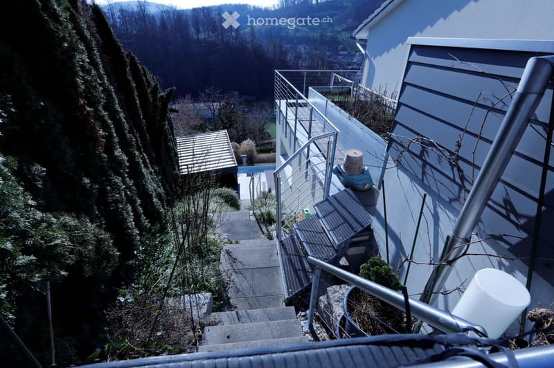 grey house, metal railings, stone steps, terrace, swimming pool, trees, plants