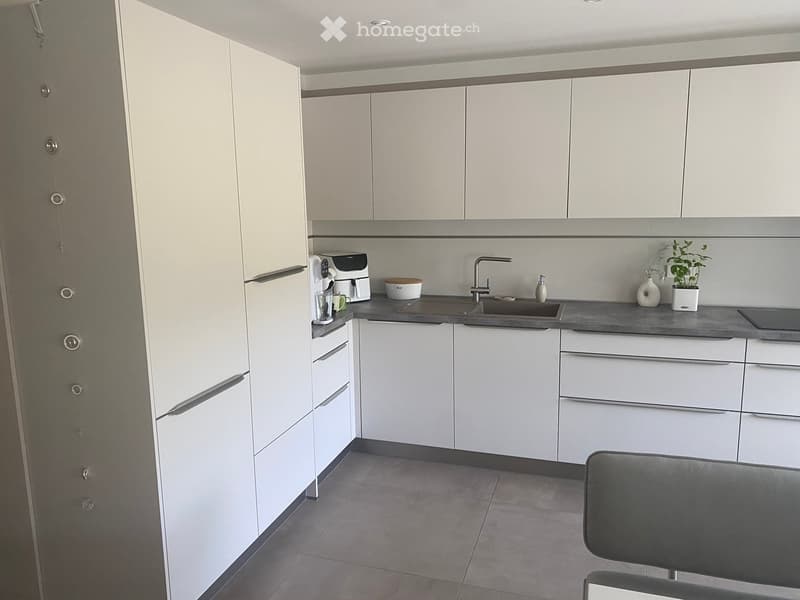 Modern kitchen with white cabinets, stainless steel sink, and various appliances on the counter.