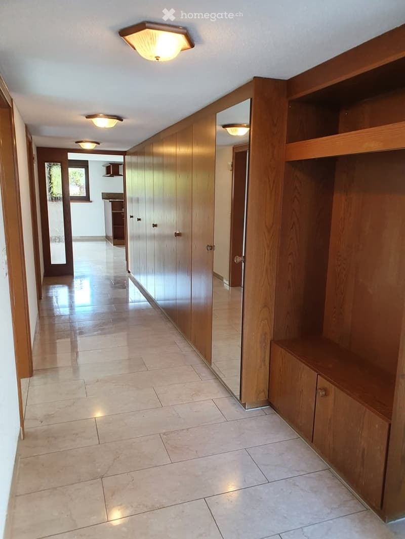 Empty hallway with wooden cabinets, tiled floor, and ceiling lights