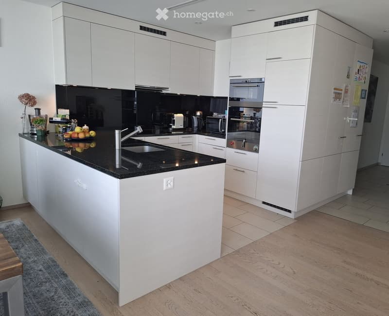 Modern kitchen with white cabinets, black countertops, stainless steel appliances, and a central island with a sink and faucet.