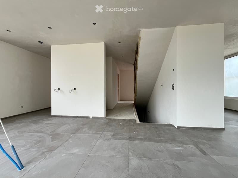 Empty room with grey tiled floor, white walls, and exposed ceiling beams. No furniture or equipment present.