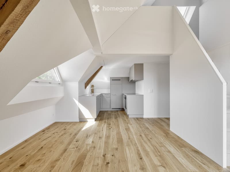 Modern kitchen with white cabinets, stainless steel appliances, and light wooden flooring.