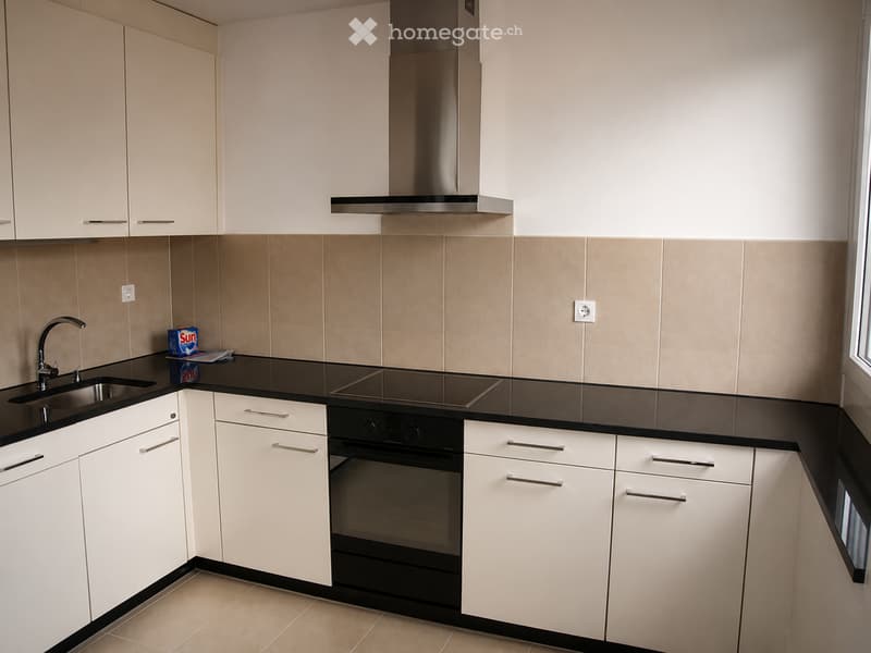 Modern kitchen with white cabinets, black countertops, stainless steel appliances, and a sleek design.