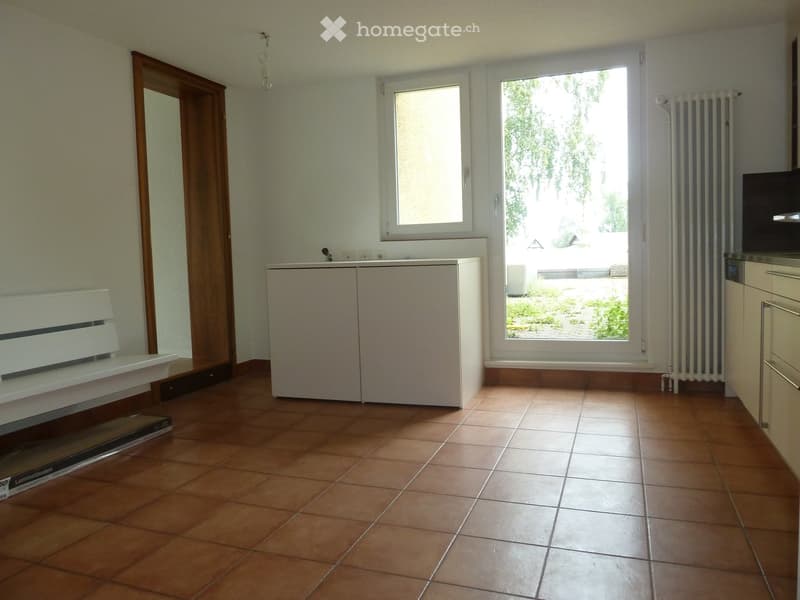 Empty room with tiled floor, white walls, large window, radiator, and cabinet.