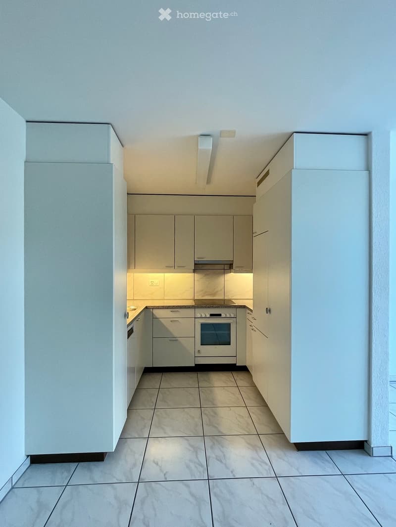Modern kitchen with light-colored cabinets, a built-in oven, and a tiled floor.