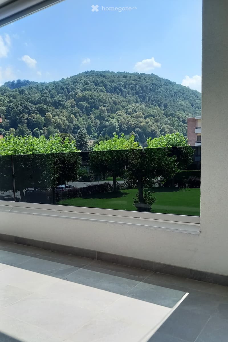 Balcony with modern glass railing, tiled floor, and scenic mountain view.
