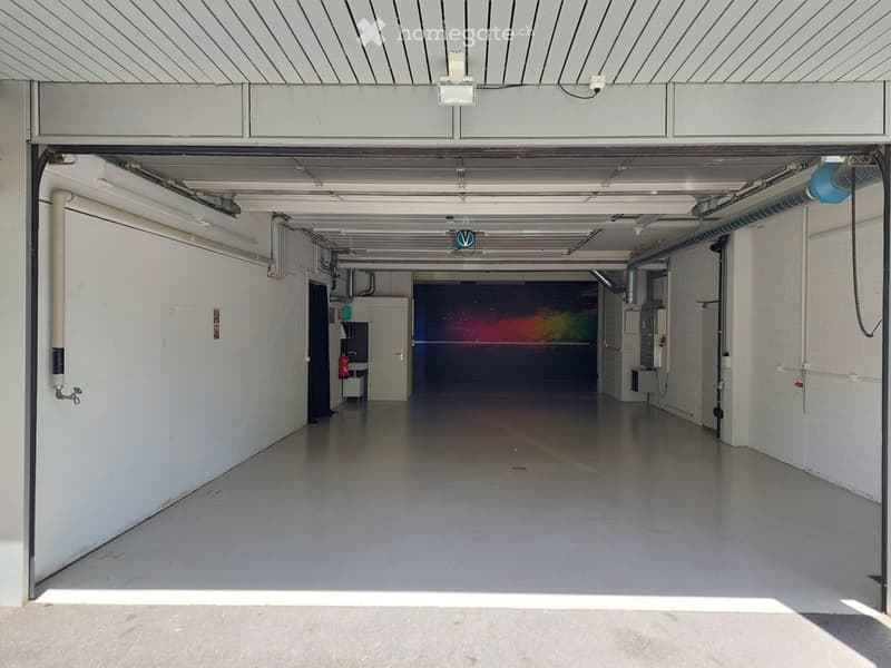 {"visible_features": ["Garage"], "type": "Garage", "objects": [], "description": "Empty underground garage with white walls, concrete floor, and a large open space. Features include a fire extinguisher, a sink, and a colorful mural on the back wall.", "lo