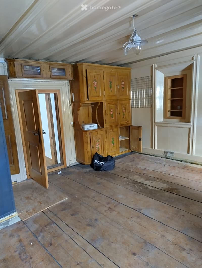Empty room with wooden floor, wooden cabinets, and a chandelier. No furniture or equipment.