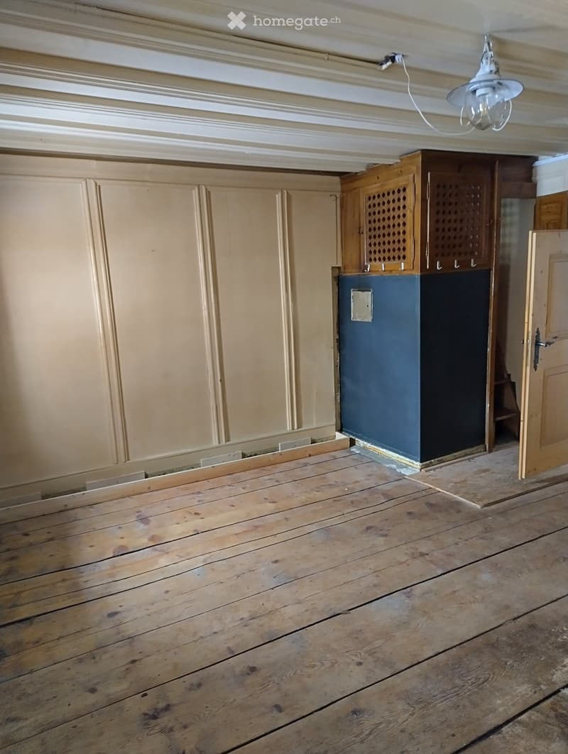 Empty room with wooden floor, light-colored walls, and a dark blue pillar. No furniture or equipment is present.