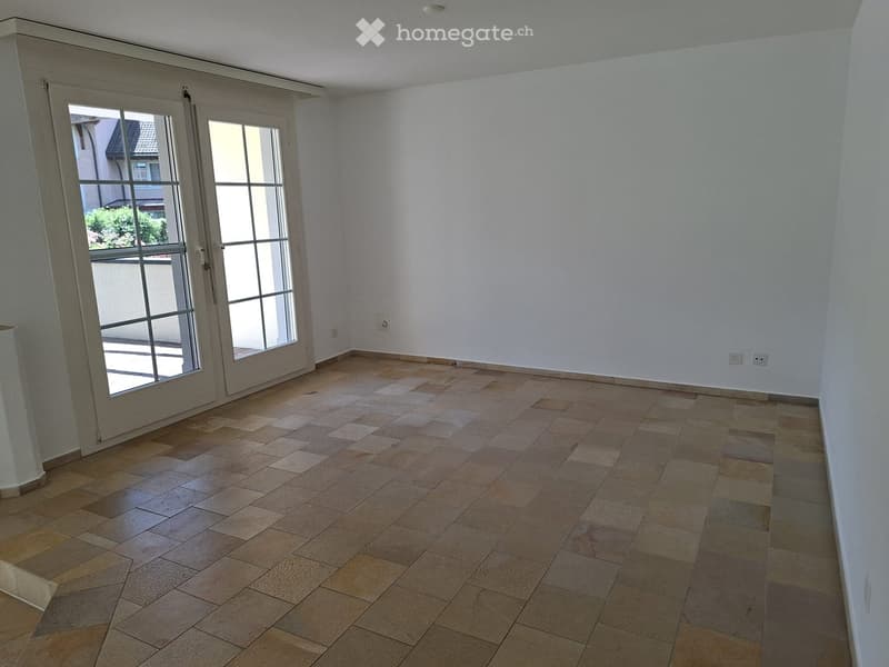 Empty room with tiled floor and large glass doors leading outside.
