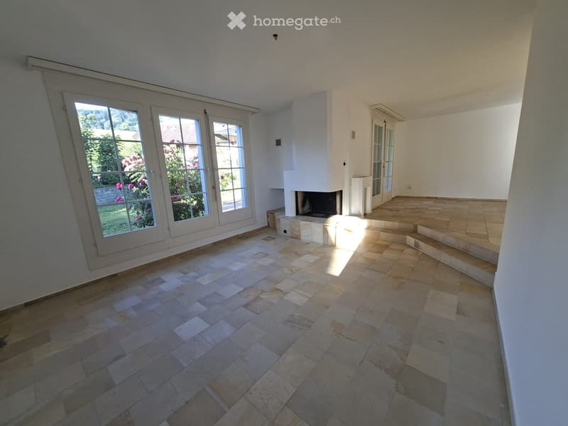 Empty room with tiled flooring, large windows, and a fireplace. No furniture or equipment present.