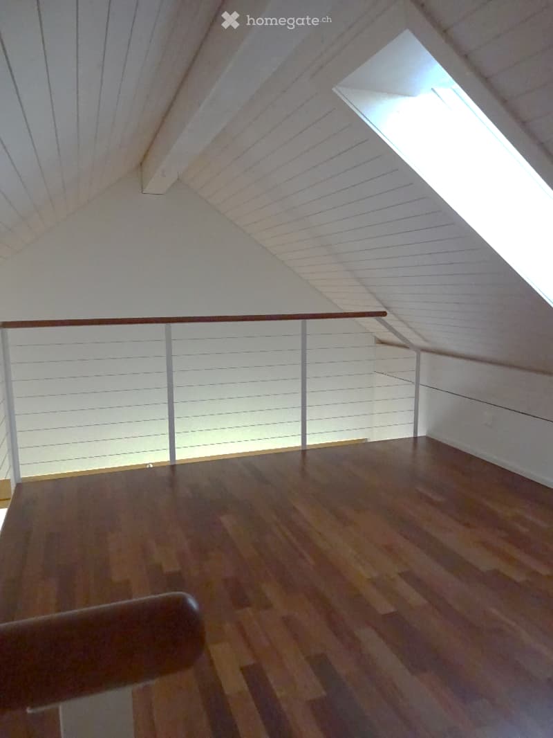 Modern interior staircase with wooden steps and white walls, featuring a skylight window at the top providing natural light.