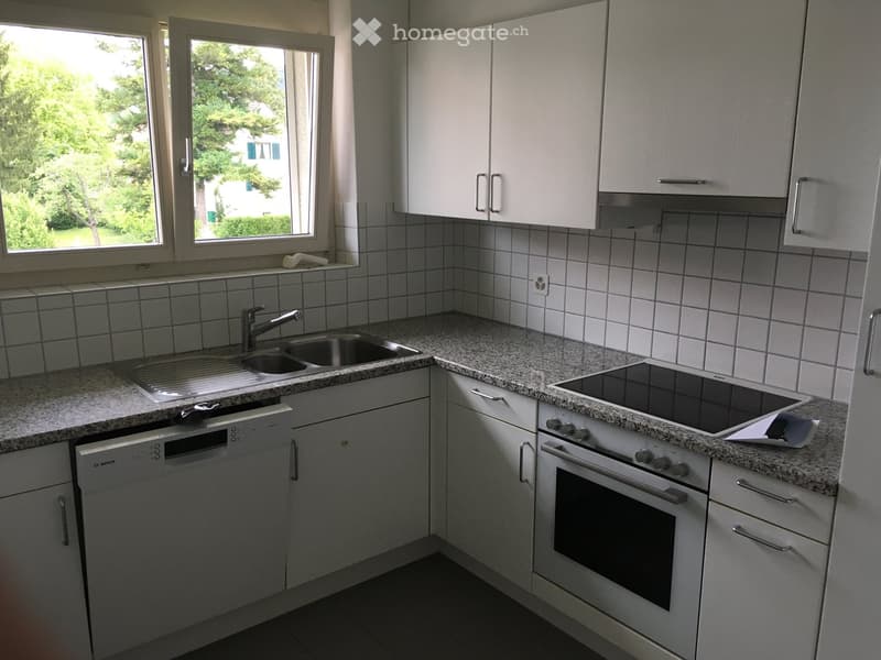 Modern kitchen with white cabinets, granite countertops, stainless steel sink, dishwasher, and electric stove.