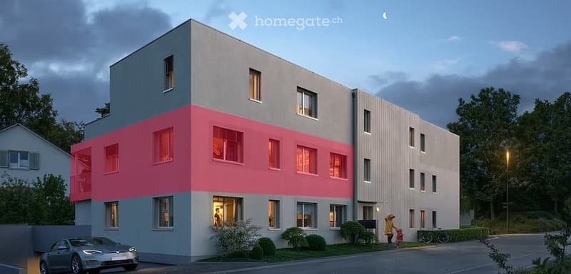 Modern multi-story building with a combination of grey and pink facades, large windows, and a contemporary design. The building is surrounded by small shrubs and trees, with a parked car visible in the foreground.