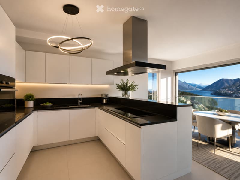 Modern kitchen with white cabinets, black countertops, a large window offering a scenic view, and a small dining area with a table and chairs.