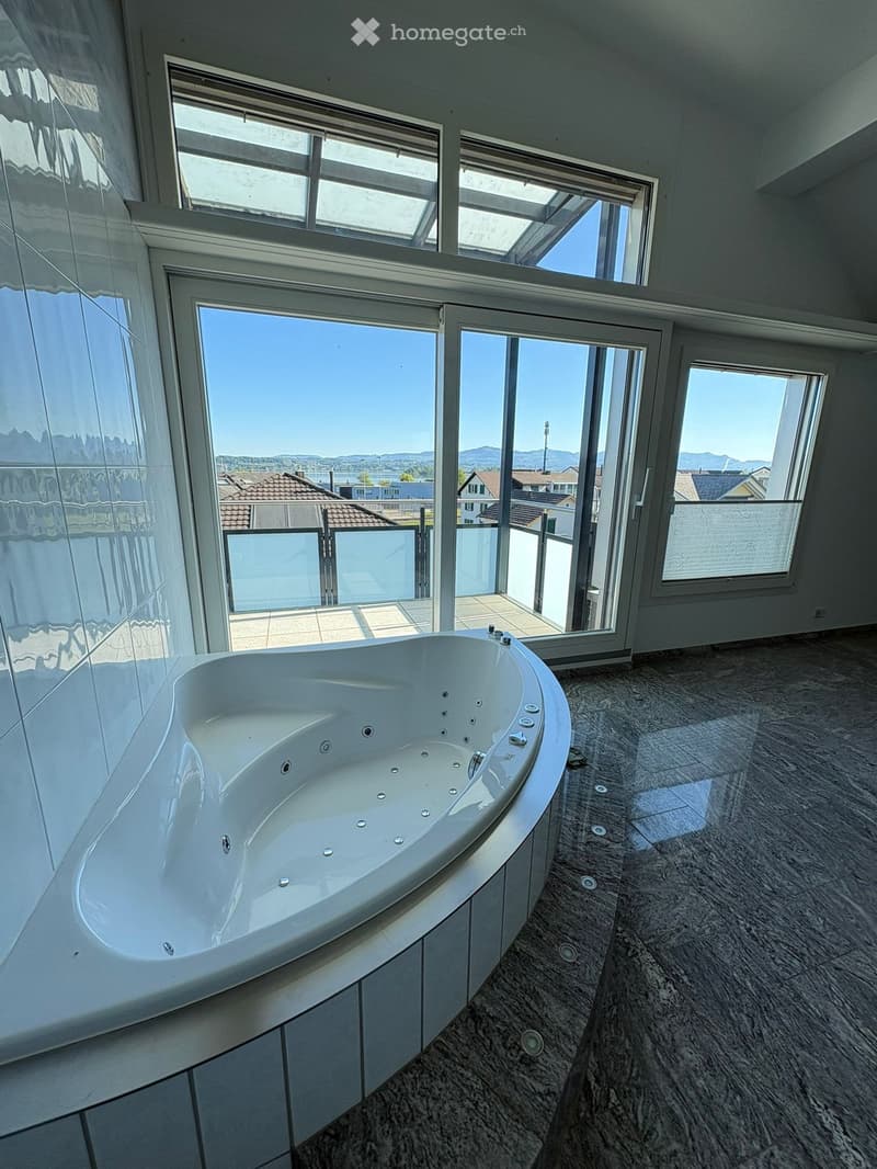 large bathtub, large windows, balcony, tiled floor, gray walls