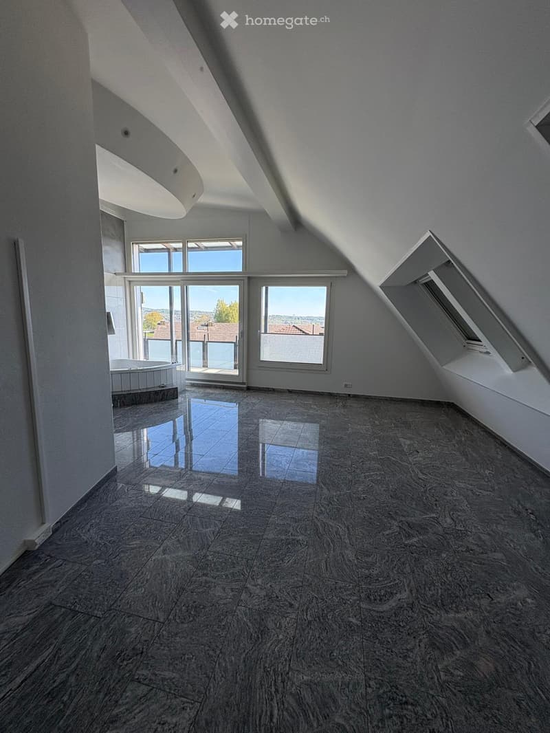 Empty room with large windows, marble floor, bathtub, slanted ceiling