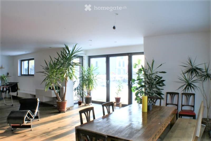 Bright, open dining area with large sliding glass doors leading to a balcony, wooden table, chairs, and several potted plants.