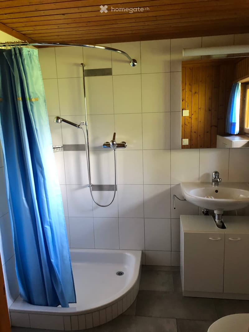 Bathroom with a bathtub, shower curtain, faucet, sink, and cabinet.