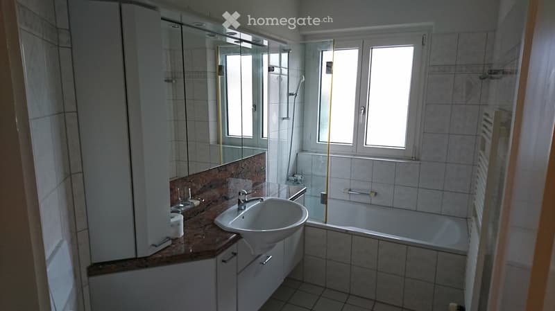 Bathroom with bathtub, sink, mirror, and tiled walls