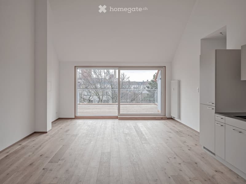 Bright, unfurnished room with wooden flooring, white walls, and a large sliding glass door leading to a balcony.