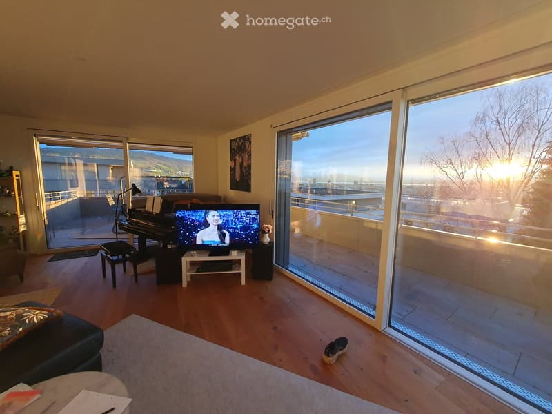 Modern living room with large windows offering a scenic view, featuring a sofa, coffee table, piano, television, and floor lamp.