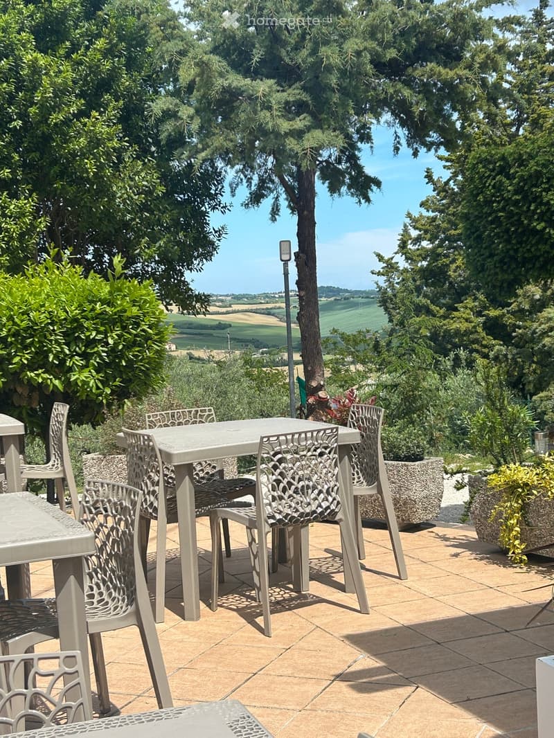 Outdoor patio with a table and chairs, surrounded by trees and greenery, offering a scenic countryside view.