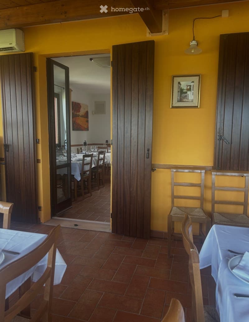 Dining area with wooden chairs and tables, yellow walls, and a picture frame on the wall.