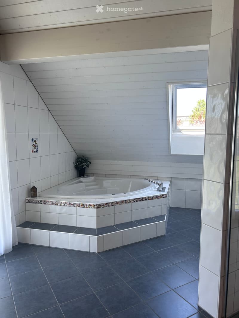 Bathroom with a large bathtub, white tiles, a window, and a potted plant