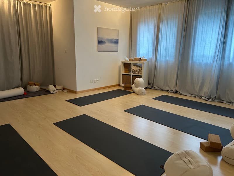 Yoga room with wooden floor, white walls, yoga mats, yoga blocks, yoga balls, and a shelf with items