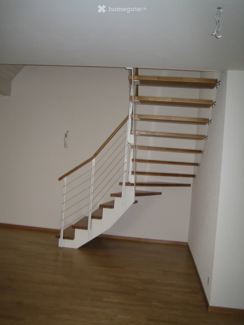 white walls, wooden floor, white and brown staircase, white railings
