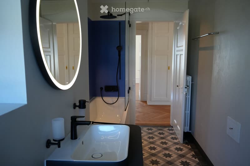 Bathroom with white sink, blue wall, mirror, bathtub, shower, wooden floor
