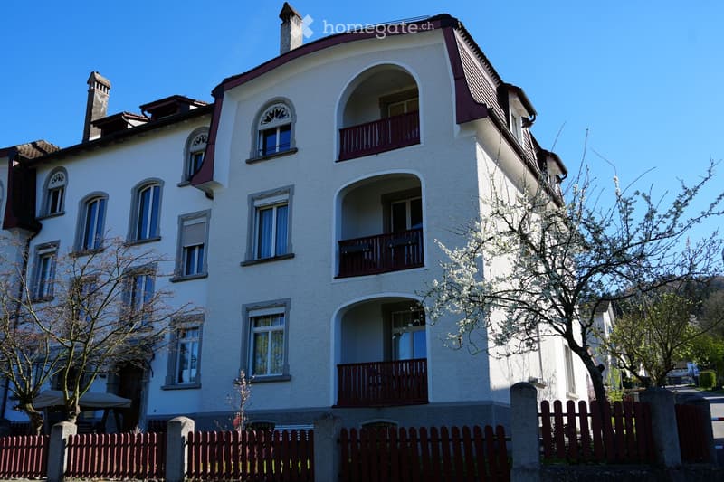 white building, multiple windows, red balconies, red fence, trees