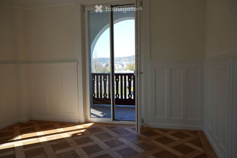 empty room, wooden parquet floor, white walls, sliding glass door, balcony with railings, view of the city