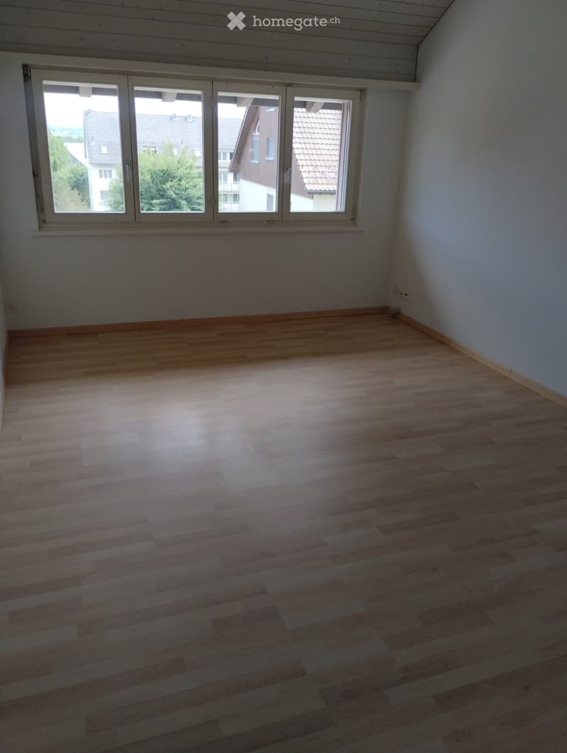 Empty room with wooden flooring and large windows, no furniture or equipment present.