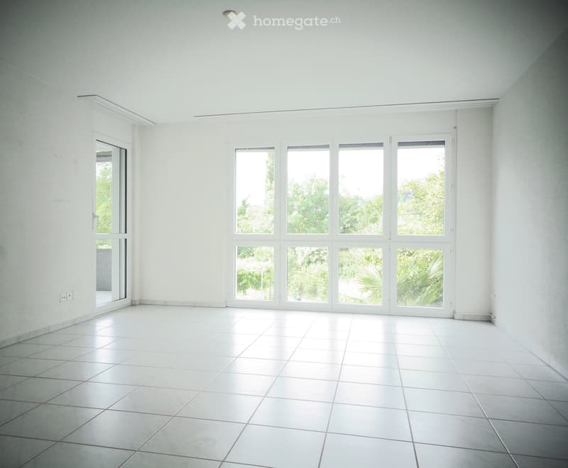 Empty room with white tiled flooring, large windows, and white walls. No furniture or equipment present.