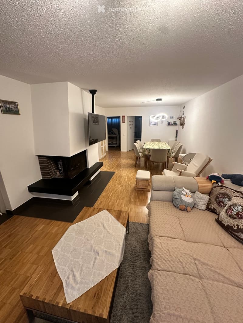 Modern living room with a fireplace, sofa, coffee table, dining area, and decorative pillows.