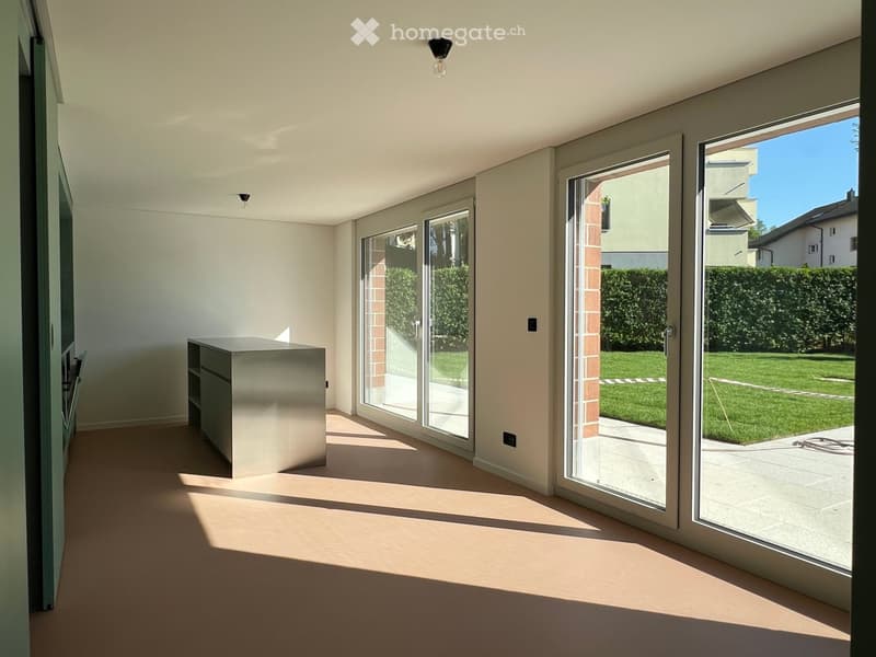Bright, modern room with large sliding glass doors leading to a garden, featuring a sleek cabinet and neutral tones.