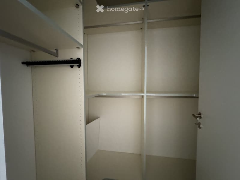 Empty closet with multiple shelves and hanging rods, no items stored inside.